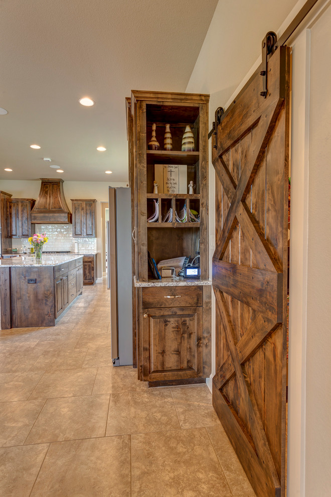 Photo of a large rustic l-shaped open plan kitchen in Austin with a submerged sink, raised-panel cabinets, dark wood cabinets, granite worktops, white splashback, metro tiled splashback, stainless steel appliances, ceramic flooring, an island, beige floors and multicoloured worktops.