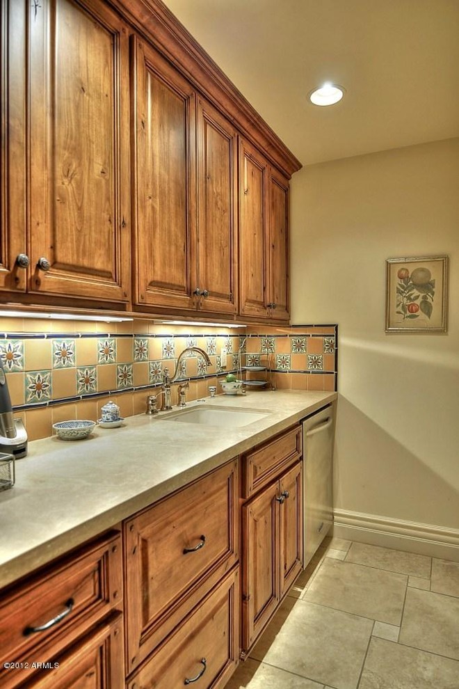 Eat-in kitchen - mid-sized southwestern galley ceramic tile eat-in kitchen idea in Phoenix with a drop-in sink, multicolored backsplash, mosaic tile backsplash, stainless steel appliances, an island, raised-panel cabinets, medium tone wood cabinets and limestone countertops