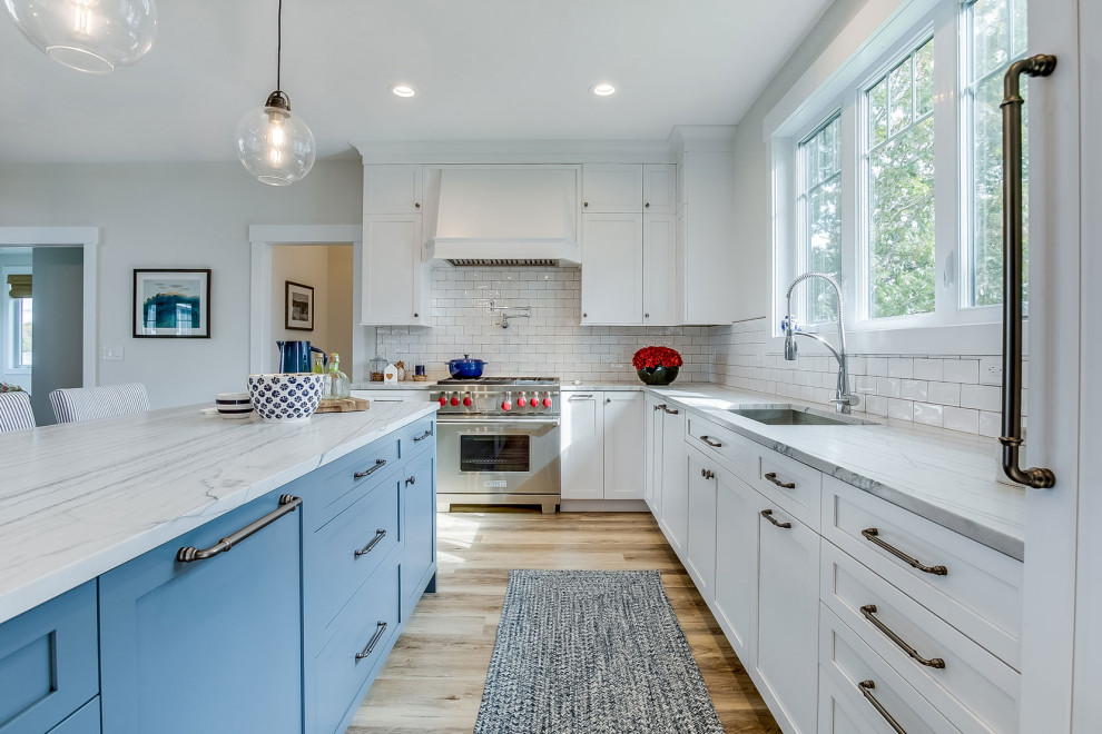 Example of a large transitional l-shaped beige floor kitchen design in Other with an undermount sink, shaker cabinets, white cabinets, white backsplash, ceramic backsplash, stainless steel appliances, an island and gray countertops