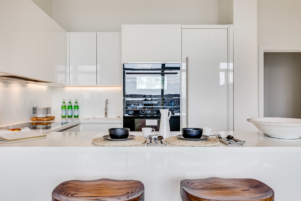 Kitchen - small modern u-shaped kitchen idea in London with an undermount sink, flat-panel cabinets, white cabinets, white backsplash and white countertops