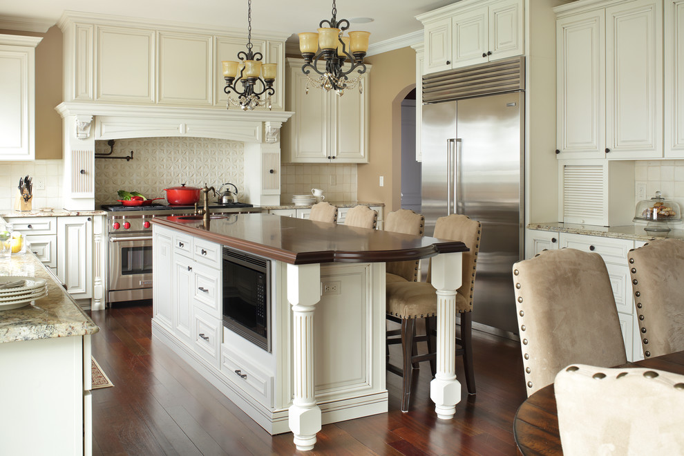 Example of a large transitional l-shaped medium tone wood floor eat-in kitchen design in New York with raised-panel cabinets, white cabinets, white backsplash, an island, an undermount sink, granite countertops, ceramic backsplash and stainless steel appliances