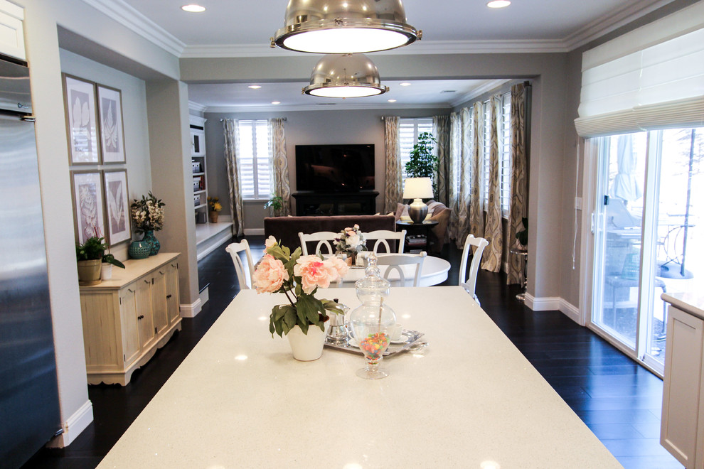 Photo of a large classic u-shaped open plan kitchen in San Francisco with a belfast sink, recessed-panel cabinets, white cabinets, engineered stone countertops, white splashback, porcelain splashback, stainless steel appliances, dark hardwood flooring and an island.