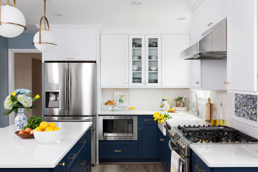 Klassisk inredning av ett mellanstort l-kök, med en rustik diskho, skåp i shakerstil, blå skåp, bänkskiva i kvarts, vitt stänkskydd, en köksö, mellanmörkt trägolv och brunt golv