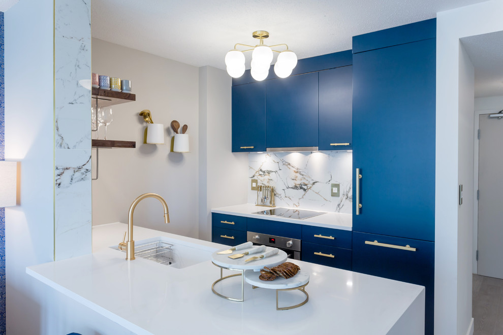 Medium sized contemporary galley kitchen/diner in Vancouver with a submerged sink, flat-panel cabinets, blue cabinets, white splashback, integrated appliances, white worktops, composite countertops, marble splashback, dark hardwood flooring, a breakfast bar and brown floors.