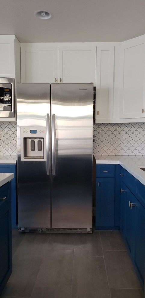 Bild på ett mellanstort vintage vit vitt u-kök, med en undermonterad diskho, skåp i shakerstil, blå skåp, bänkskiva i kvarts, vitt stänkskydd, stänkskydd i keramik, rostfria vitvaror, cementgolv, en köksö och grått golv