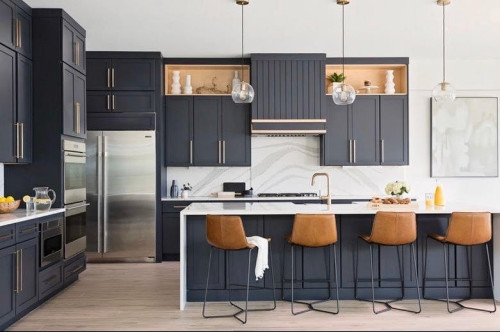 Contemporary kitchen with navy blue RTA cabinets, white quartz countertops, and leather bar stools