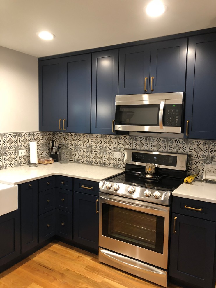 Bild på ett mellanstort funkis vit vitt kök, med en rustik diskho, skåp i shakerstil, blå skåp, bänkskiva i kvarts, flerfärgad stänkskydd, stänkskydd i stenkakel, rostfria vitvaror, laminatgolv och brunt golv