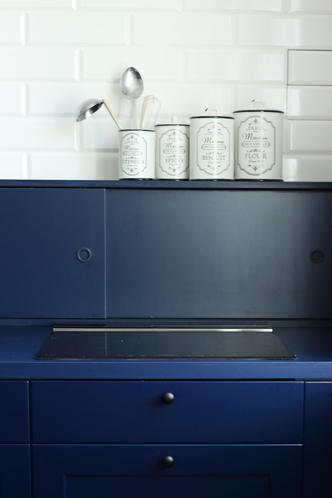 Idéer för att renovera ett mellanstort industriellt blå blått kök, med en enkel diskho, luckor med profilerade fronter, blå skåp, laminatbänkskiva, blått stänkskydd, stänkskydd i tegel, svarta vitvaror, klinkergolv i porslin, en köksö och blått golv