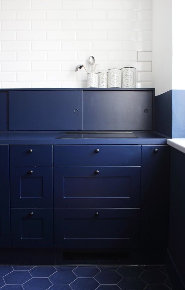 Foto på ett mellanstort industriellt blå kök, med en enkel diskho, luckor med profilerade fronter, blå skåp, laminatbänkskiva, blått stänkskydd, stänkskydd i tegel, svarta vitvaror, klinkergolv i porslin, en köksö och blått golv