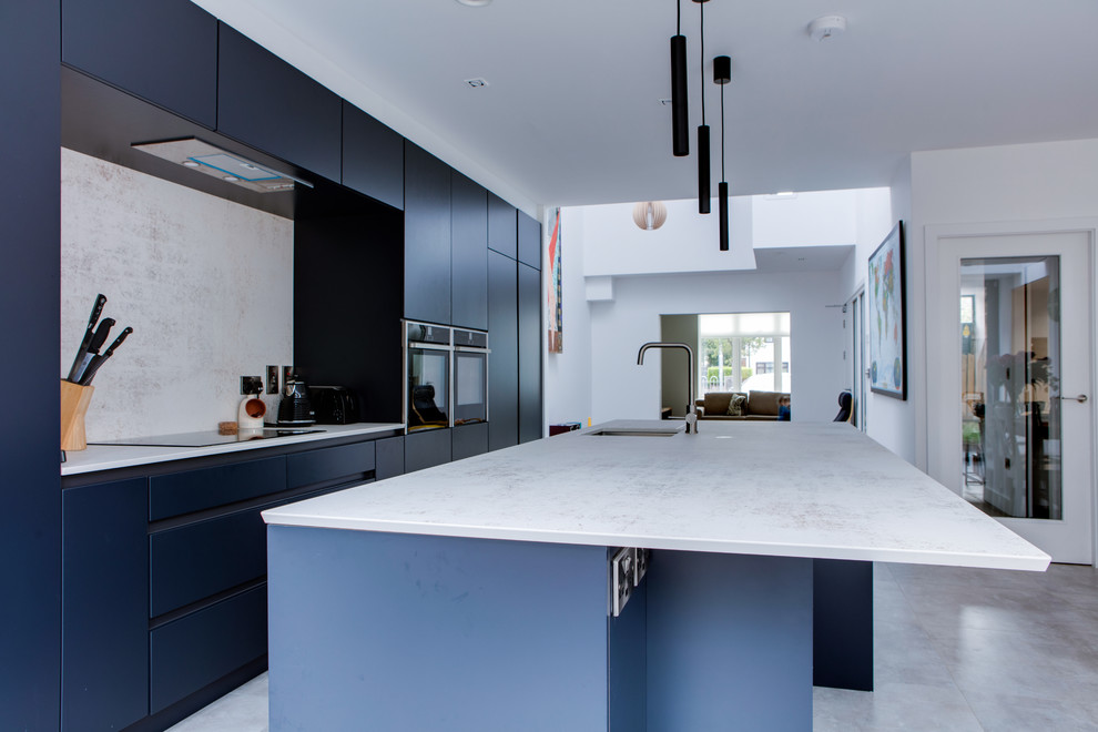 Inredning av ett modernt mellanstort grå grått kök, med en nedsänkt diskho, släta luckor, blå skåp, bänkskiva i kvartsit, grått stänkskydd, stänkskydd i sten, rostfria vitvaror, klinkergolv i porslin, en köksö och grått golv