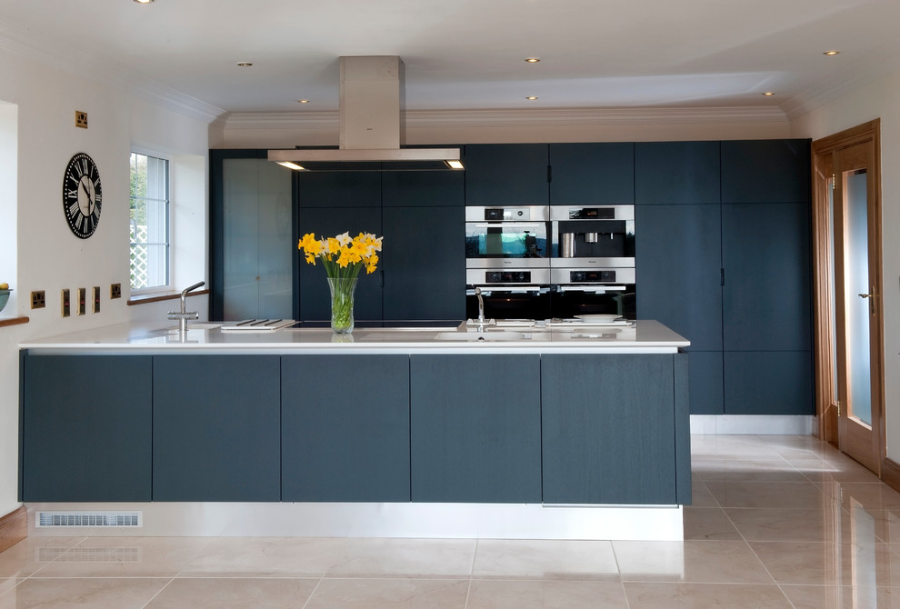 This is an example of a contemporary kitchen in Cork with flat-panel cabinets, black cabinets, stainless steel appliances, a breakfast bar and beige floors.