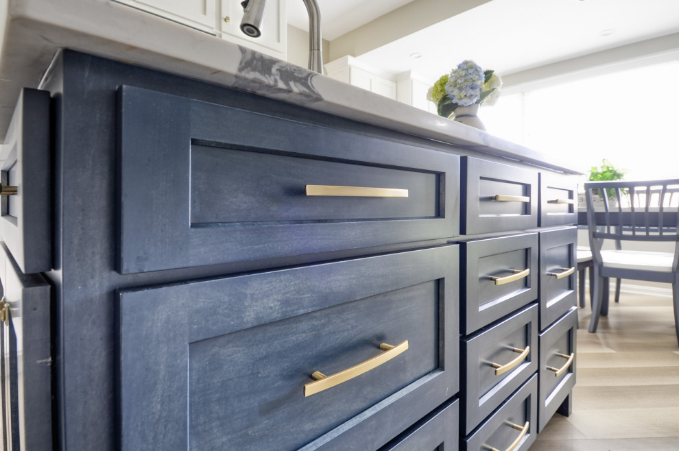 Example of a mid-sized transitional u-shaped laminate floor and gray floor open concept kitchen design in DC Metro with an undermount sink, shaker cabinets, white cabinets, quartzite countertops, stainless steel appliances, an island and white countertops