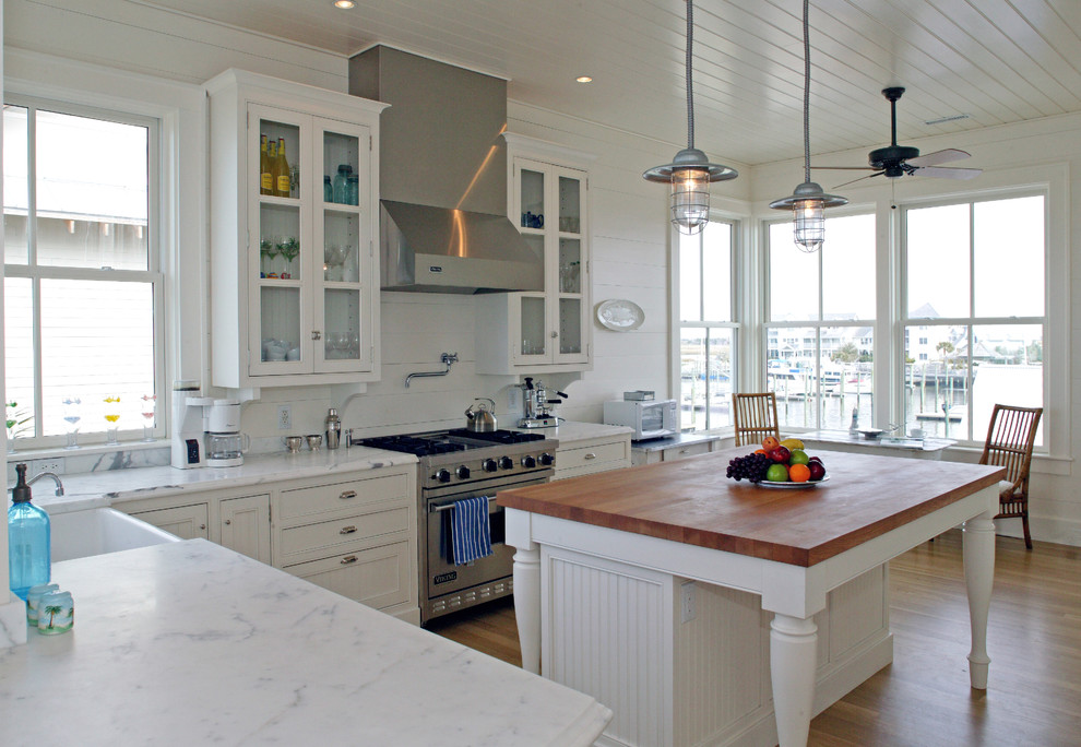 Example of a classic kitchen design in Wilmington with stainless steel appliances, wood countertops, a farmhouse sink, white cabinets, white backsplash and beaded inset cabinets