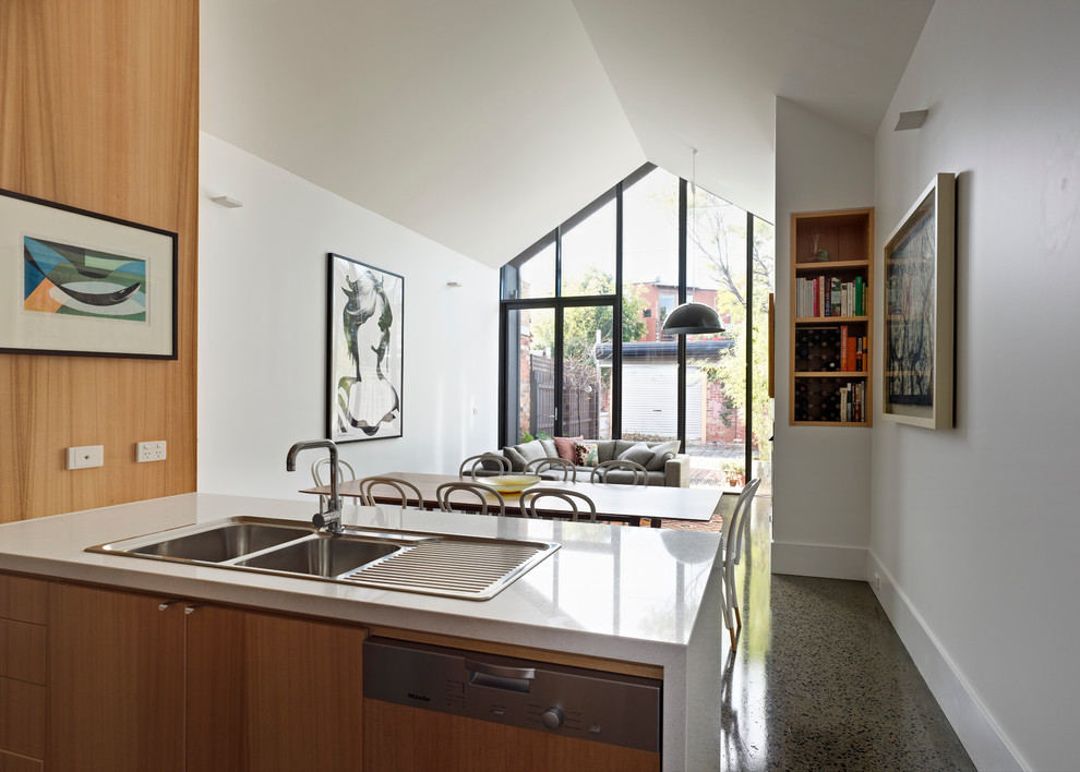 Ejemplo de cocina lineal actual pequeña abierta con armarios con paneles lisos, puertas de armario de madera clara, encimera de granito y una isla