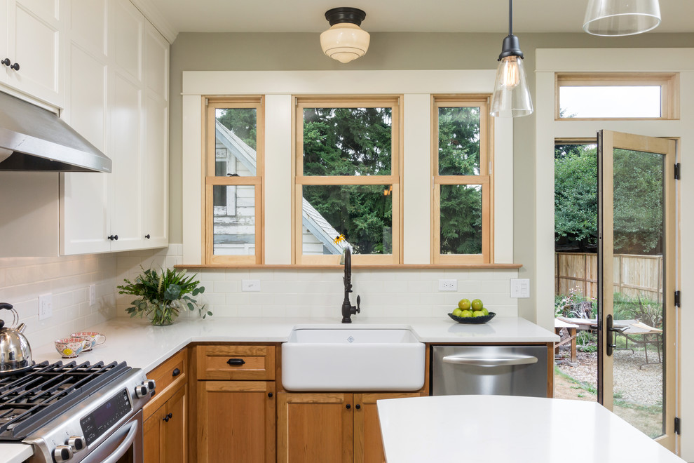 Foto på ett mellanstort, avskilt amerikanskt l-kök, med en rustik diskho, skåp i mellenmörkt trä, bänkskiva i kvarts, vitt stänkskydd, stänkskydd i keramik, rostfria vitvaror, klinkergolv i keramik, en köksö, luckor med infälld panel och grått golv