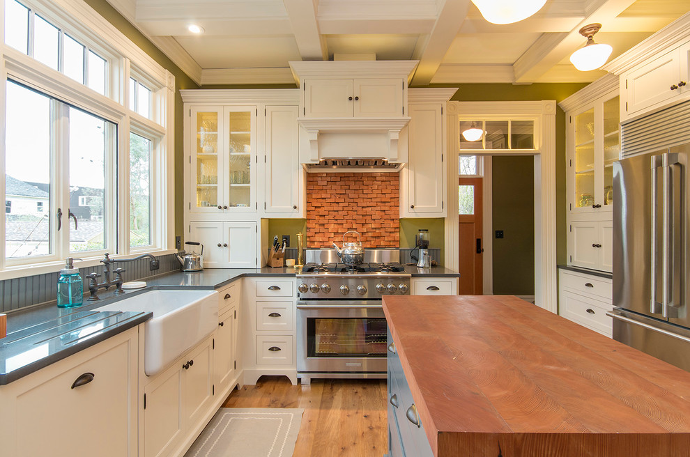 Geschlossene Klassische Küche in U-Form mit Landhausspüle, Schrankfronten mit vertiefter Füllung, weißen Schränken, Küchenrückwand in Grau, Küchengeräten aus Edelstahl, braunem Holzboden und Kücheninsel in Portland