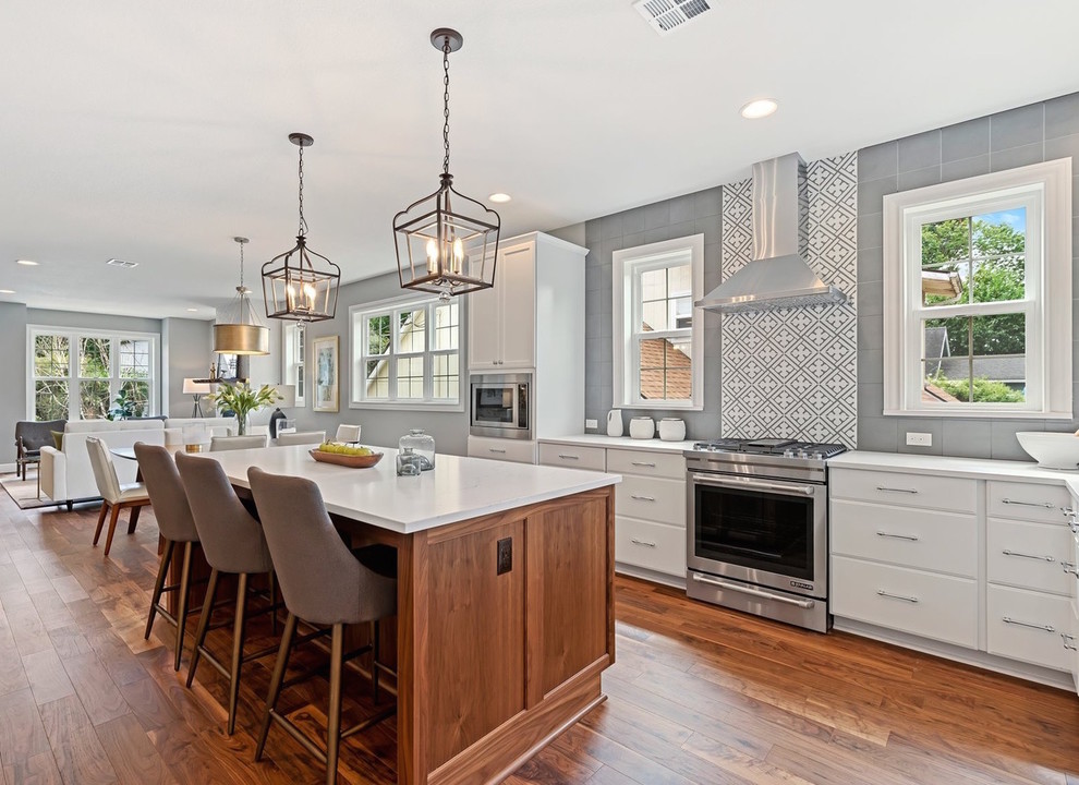 Transitional l-shaped medium tone wood floor open concept kitchen photo in Portland with white cabinets, multicolored backsplash, stainless steel appliances, an island and white countertops