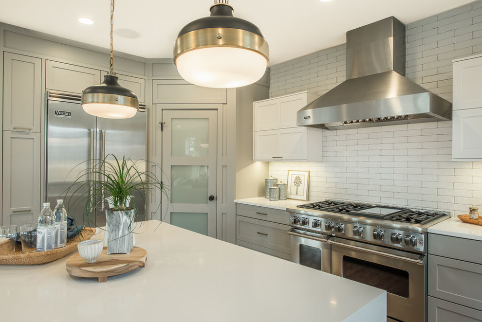 Mid-sized transitional u-shaped light wood floor and beige floor open concept kitchen photo in Seattle with an undermount sink, shaker cabinets, gray cabinets, solid surface countertops, white backsplash, subway tile backsplash, stainless steel appliances and an island