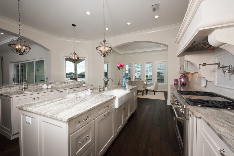 Design ideas for a large classic galley kitchen/diner in Tampa with a belfast sink, shaker cabinets, white cabinets, granite worktops, white splashback, metro tiled splashback, stainless steel appliances, dark hardwood flooring and multiple islands.