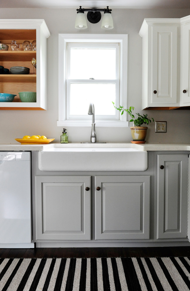 Inspiration for a mid-sized transitional l-shaped vinyl floor open concept kitchen remodel in Indianapolis with a farmhouse sink, raised-panel cabinets, white cabinets, solid surface countertops, white appliances and no island