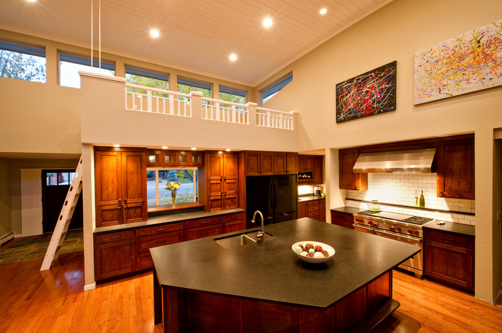 Photo of a contemporary kitchen in Denver with white splashback, metro tiled splashback and black appliances.
