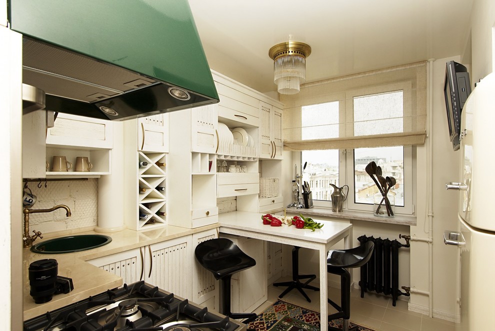 На фото: отдельная, угловая кухня в стиле шебби-шик с накладной мойкой, фасадами с утопленной филенкой, белыми фасадами, белой техникой и шторами на окнах с