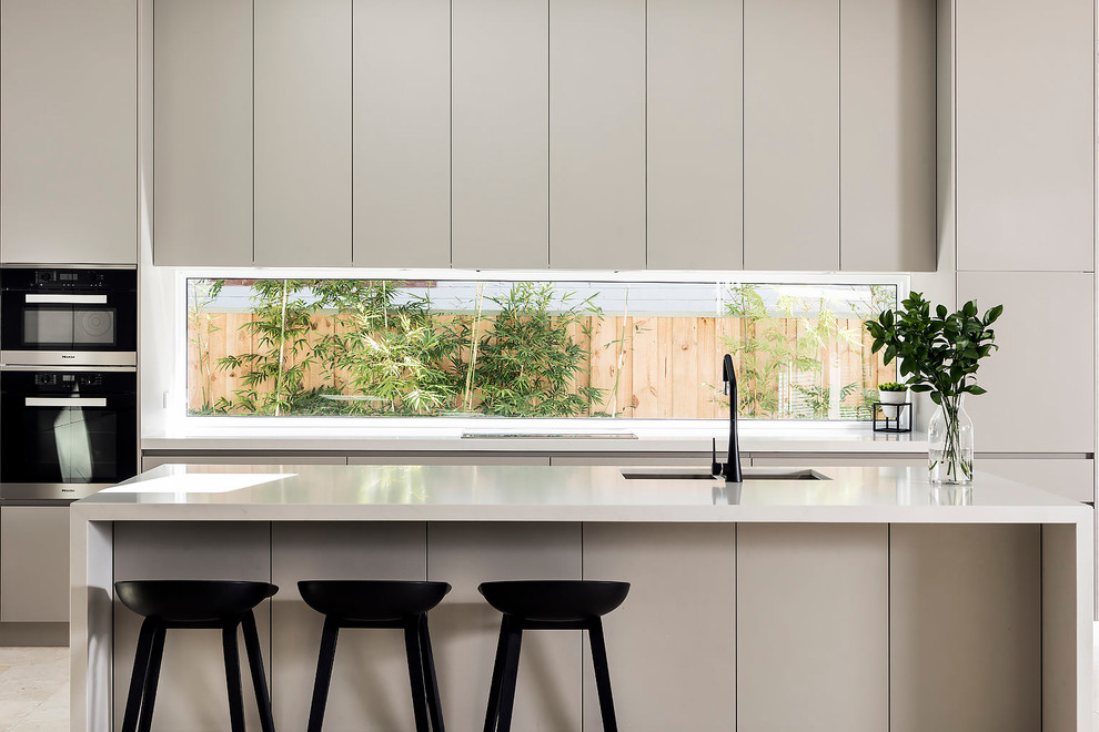 Exempel på ett stort modernt kök, med en undermonterad diskho, grå skåp, bänkskiva i kvarts, fönster som stänkskydd, rostfria vitvaror, travertin golv, en köksö och beiget golv