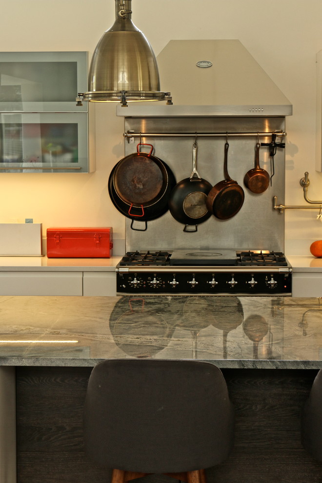 Bild på ett stort funkis l-kök, med en dubbel diskho, släta luckor, vita skåp, mellanmörkt trägolv och en köksö