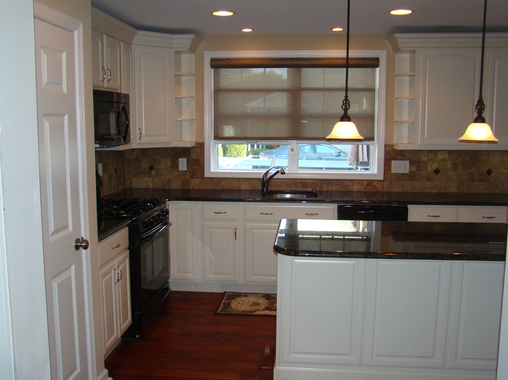 Inredning av ett klassiskt avskilt, mellanstort l-kök, med en undermonterad diskho, luckor med upphöjd panel, vita skåp, granitbänkskiva, beige stänkskydd, stänkskydd i stenkakel, svarta vitvaror och en köksö