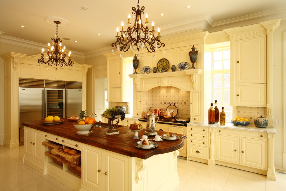 Inredning av ett avskilt, stort l-kök, med en undermonterad diskho, luckor med upphöjd panel, vita skåp, marmorbänkskiva, beige stänkskydd, stänkskydd i porslinskakel, rostfria vitvaror, klinkergolv i porslin och en köksö