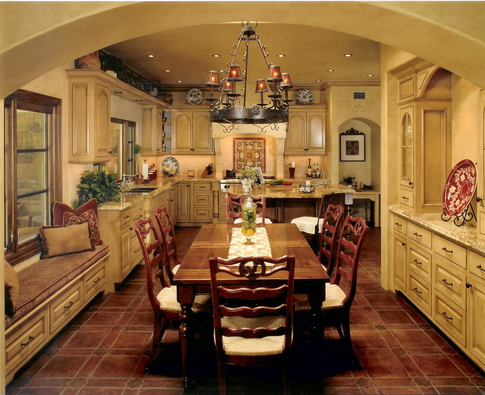 Example of a tuscan l-shaped terra-cotta tile eat-in kitchen design in Orange County with a double-bowl sink, raised-panel cabinets, distressed cabinets, granite countertops, beige backsplash, stone tile backsplash, stainless steel appliances and an island