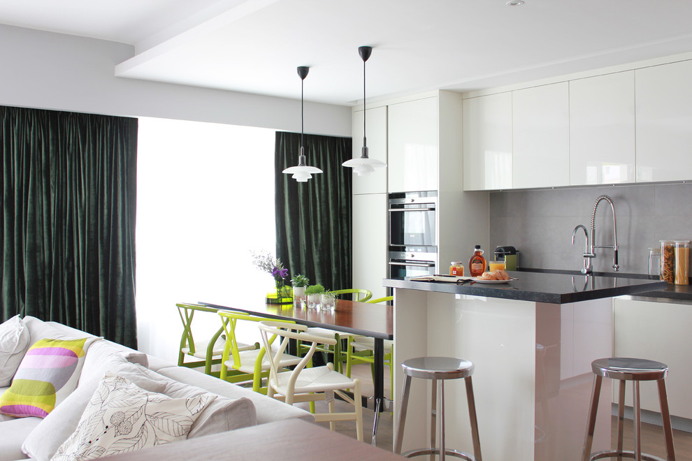 На фото: глянцевая кухня-гостиная в стиле модернизм с плоскими фасадами и белыми фасадами