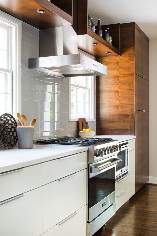Eat-in kitchen - mid-sized contemporary galley dark wood floor eat-in kitchen idea in Atlanta with an undermount sink, flat-panel cabinets, white cabinets, solid surface countertops, gray backsplash, subway tile backsplash, stainless steel appliances and an island