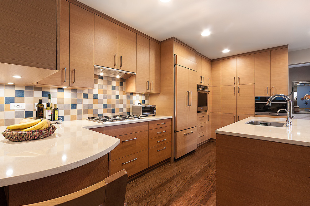 Modern inredning av ett stort vit vitt kök, med en undermonterad diskho, släta luckor, beige skåp, bänkskiva i kvarts, flerfärgad stänkskydd, stänkskydd i mosaik, rostfria vitvaror, mellanmörkt trägolv, flera köksöar och brunt golv