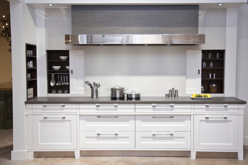 Immagine di una cucina minimal di medie dimensioni con ante bianche, paraspruzzi bianco e elettrodomestici in acciaio inossidabile