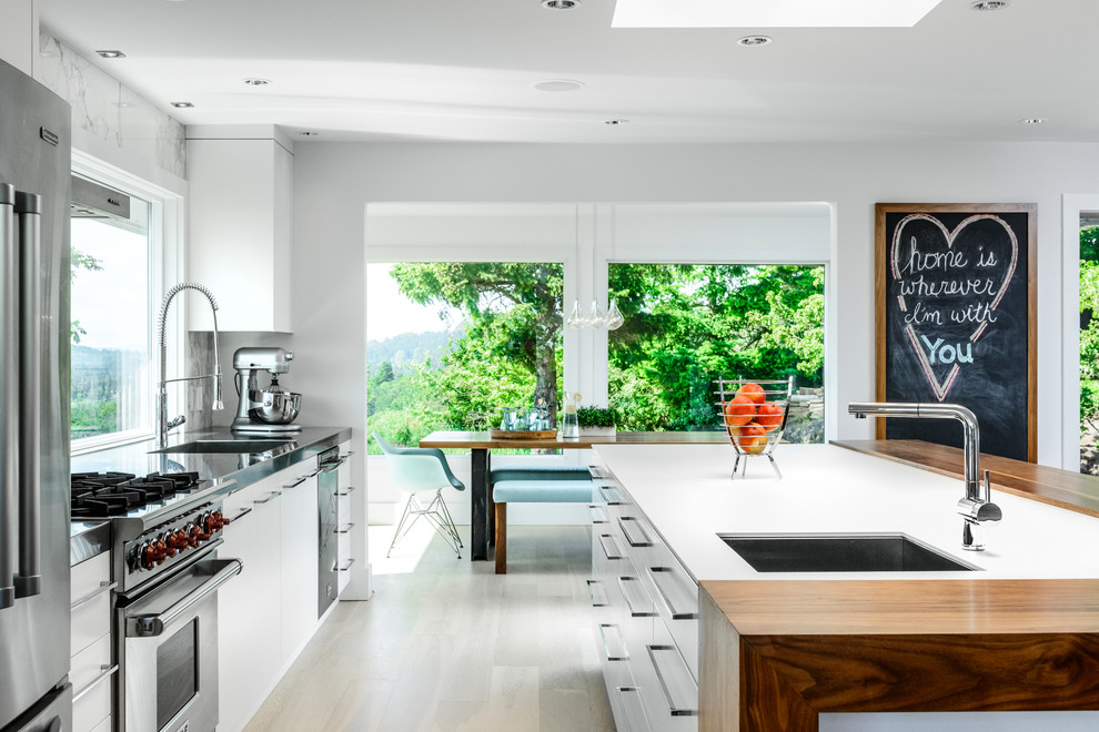 Immagine di una cucina minimal di medie dimensioni con lavello sottopiano, nessun'anta, ante bianche, elettrodomestici in acciaio inossidabile e parquet chiaro