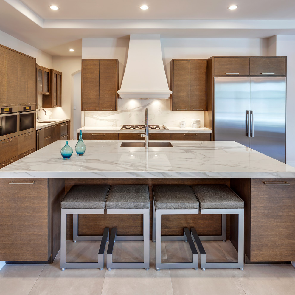 Large trendy beige floor open concept kitchen photo in Essex with a drop-in sink, flat-panel cabinets, medium tone wood cabinets, marble countertops, white backsplash, marble backsplash, stainless steel appliances and an island