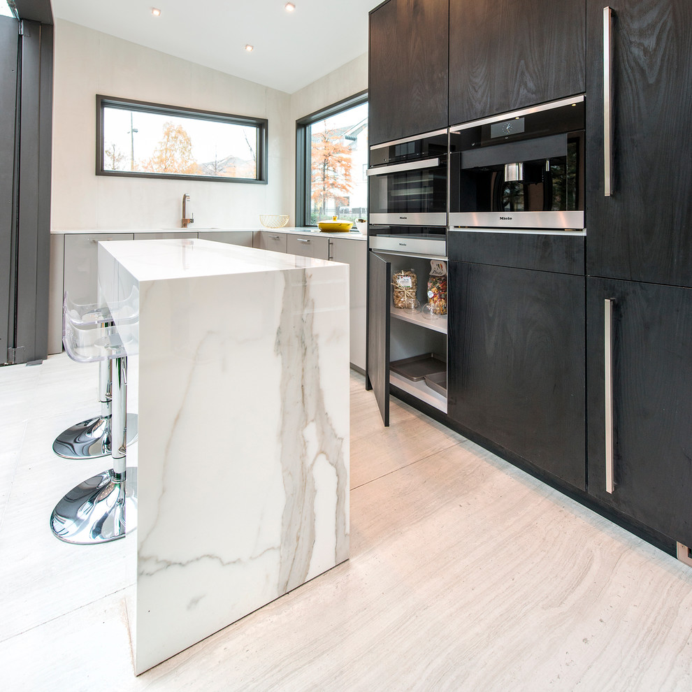 Exempel på ett modernt kök, med en nedsänkt diskho, släta luckor, skåp i mörkt trä, marmorbänkskiva, vitt stänkskydd, svarta vitvaror, en halv köksö och beiget golv