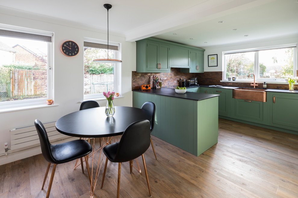 Design ideas for a medium sized traditional u-shaped kitchen/diner in Kent with a belfast sink, shaker cabinets, green cabinets, engineered stone countertops, metal splashback, lino flooring, a breakfast bar and green floors.