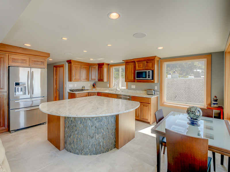 Photo of a large coastal l-shaped kitchen/diner in Portland with a submerged sink, raised-panel cabinets, medium wood cabinets, stainless steel appliances, an island, ceramic flooring, beige floors and multicoloured worktops.