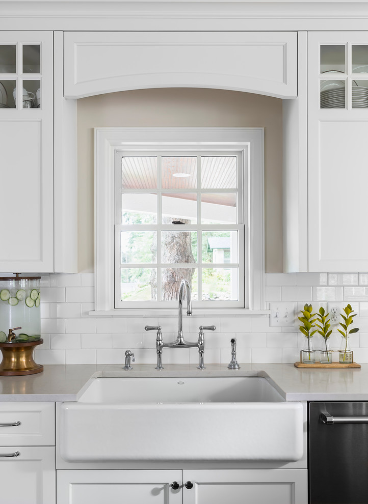 Eat-in kitchen - mid-sized transitional l-shaped medium tone wood floor eat-in kitchen idea in Minneapolis with a farmhouse sink, white cabinets, white backsplash, subway tile backsplash, stainless steel appliances, an island, shaker cabinets and quartzite countertops