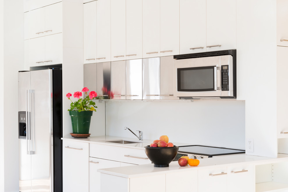 Cette image montre une cuisine américaine linéaire minimaliste de taille moyenne avec un évier 1 bac, des portes de placard blanches, parquet clair et aucun îlot.