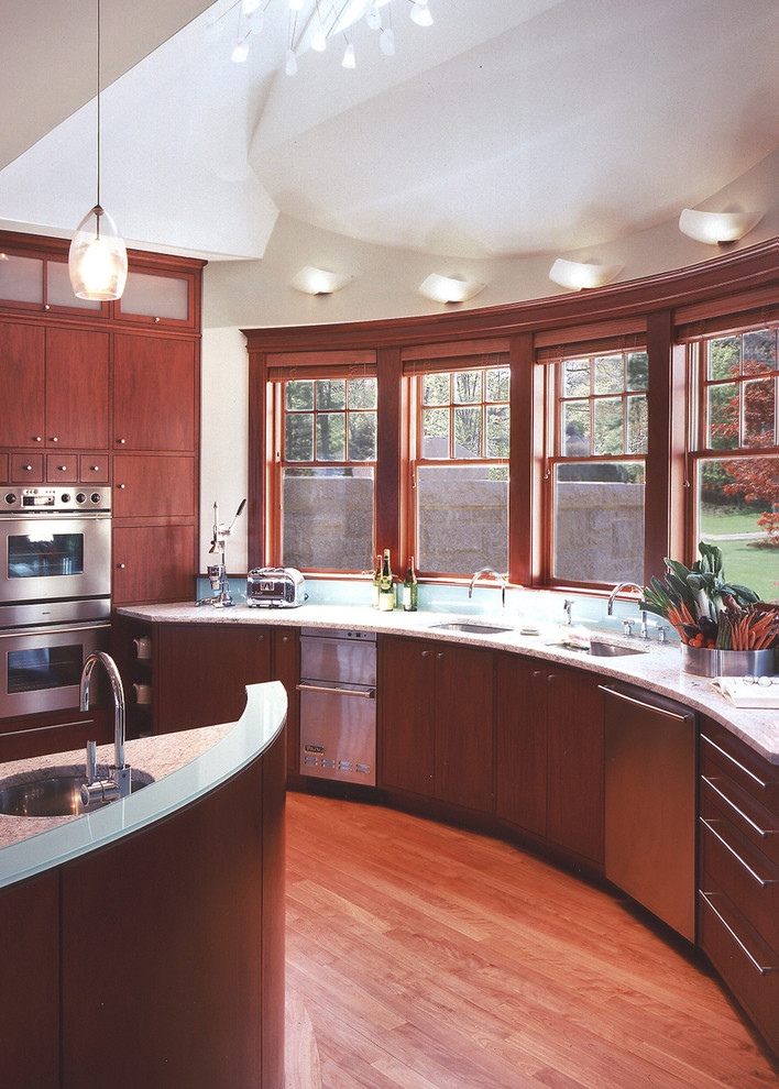 Idées déco pour une cuisine moderne en L et bois brun de taille moyenne avec un placard à porte plane, un plan de travail en verre, une crédence bleue, un électroménager en acier inoxydable, un sol en bois brun, îlot et un sol marron.