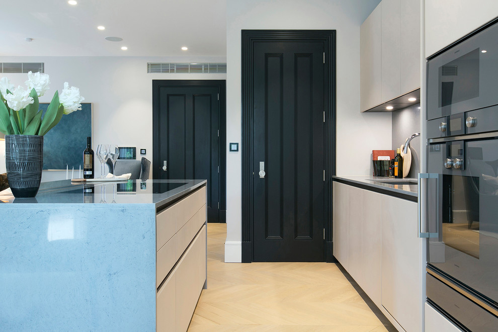 Photo of a medium sized contemporary galley open plan kitchen in London with marble worktops, medium hardwood flooring, an island, brown floors and grey worktops.