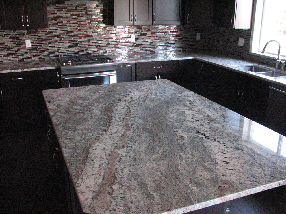 Bild på ett funkis kök, med en undermonterad diskho, skåp i shakerstil, skåp i mörkt trä, granitbänkskiva, beige stänkskydd, rostfria vitvaror, mellanmörkt trägolv och en köksö