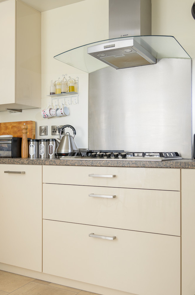Immagine di una piccola cucina moderna con ante lisce, paraspruzzi a effetto metallico, elettrodomestici da incasso, pavimento in marmo e nessuna isola