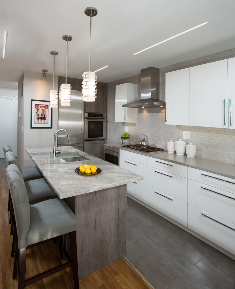 This is an example of a medium sized contemporary l-shaped kitchen in DC Metro with a submerged sink, flat-panel cabinets, white cabinets, engineered stone countertops, grey splashback, ceramic splashback, stainless steel appliances, ceramic flooring and an island.
