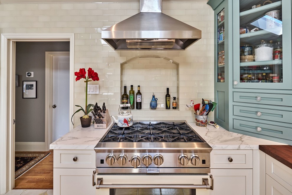 Eat-in kitchen - mid-sized farmhouse l-shaped ceramic tile eat-in kitchen idea in San Francisco with a farmhouse sink, shaker cabinets, white cabinets, marble countertops, white backsplash, glass tile backsplash, stainless steel appliances and a peninsula