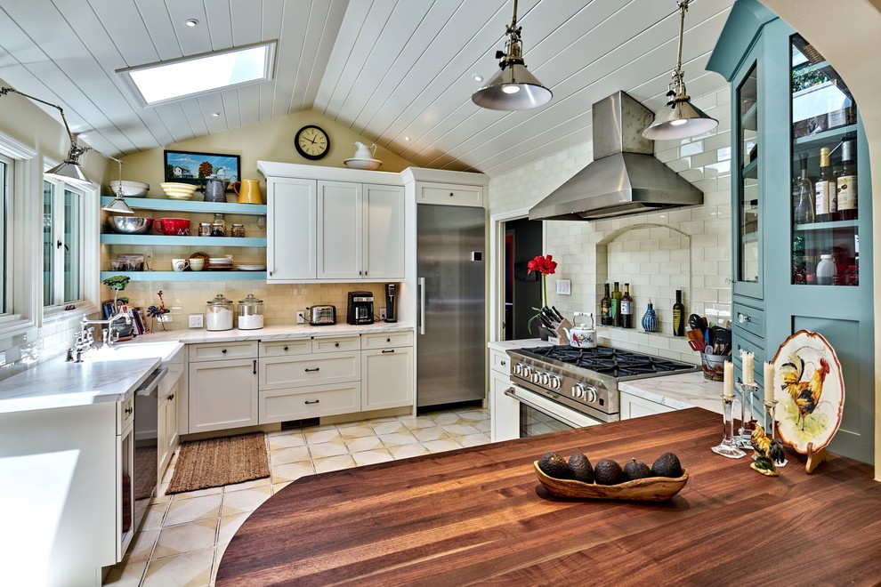 Inspiration for a mid-sized farmhouse l-shaped ceramic tile eat-in kitchen remodel in San Francisco with a farmhouse sink, shaker cabinets, yellow cabinets, marble countertops, white backsplash, glass tile backsplash, stainless steel appliances and a peninsula