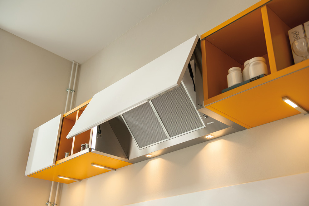 Kleine Moderne Küche in L-Form mit Waschbecken, Küchenrückwand in Weiß, Glasrückwand, Küchengeräten aus Edelstahl, Keramikboden und hellen Holzschränken in London